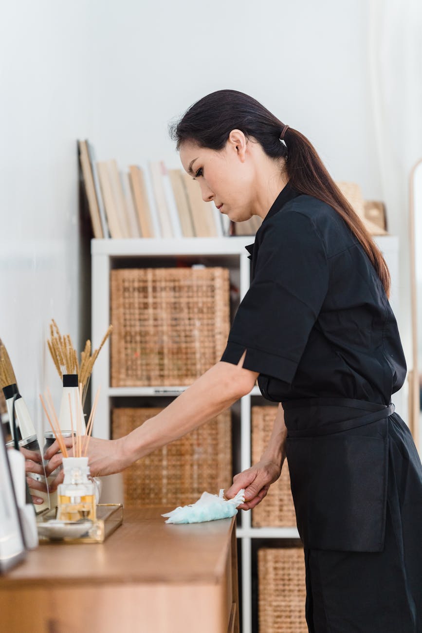 woman in black uniform holding white towel on brown wooden counter